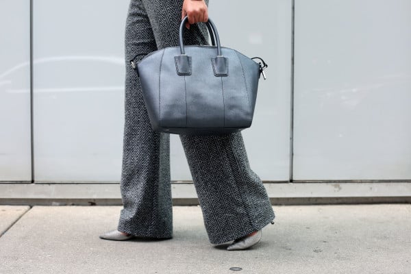 Bows & Sequins wearing a pair of wide-leg work pants, pointed toe pumps, and a metallic leather tote.