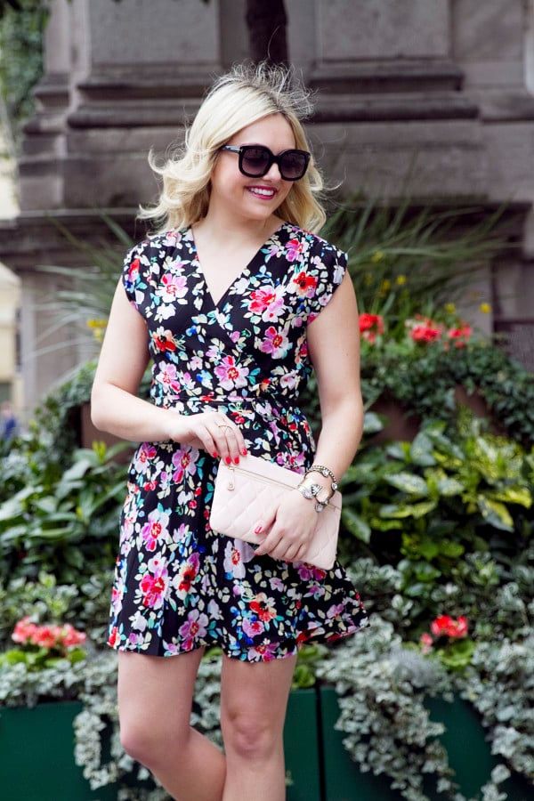 Jessica Sturdy of Bows & Sequins, a fashion-focused lifestyle blog, styling a navy floral wrap dress with a Vera Bradley blush leather clutch purse in London.