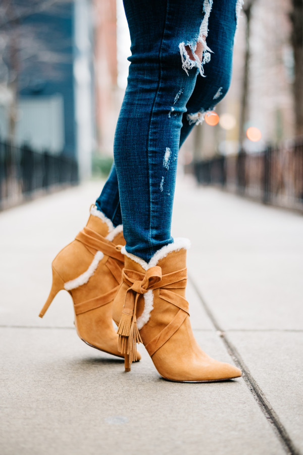 Bows & Sequins wearing a pair of Schutz shearling booties with ripped jeans.