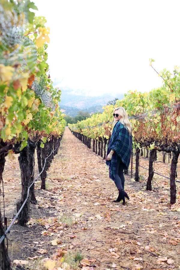Bows & Sequins wearing a plaid shirt, quilted vest, grey jeans, black booties, and a blanket scarf in Napa, California.