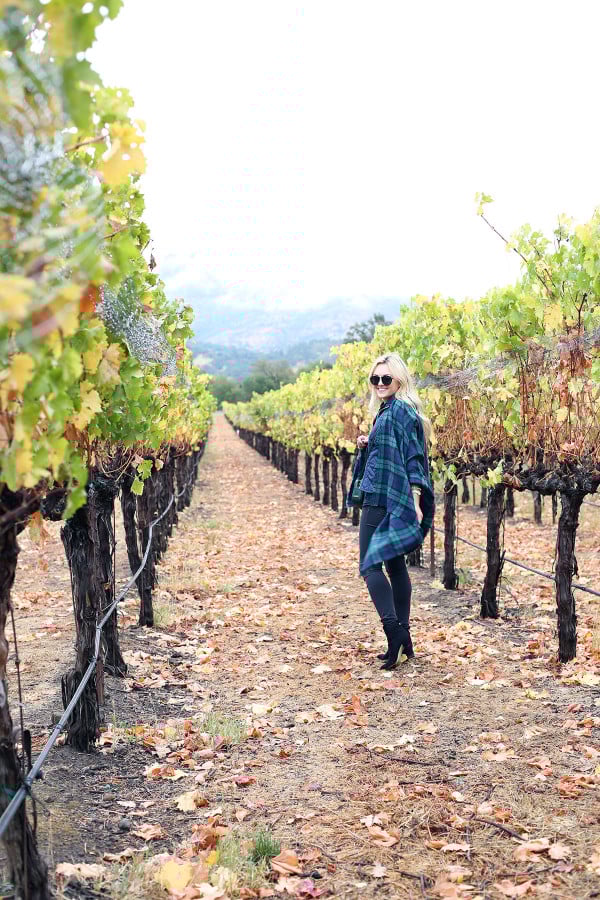 Bows & Sequins wearing a plaid shirt, quilted vest, grey jeans, black booties, and a blanket scarf in Napa, California.
