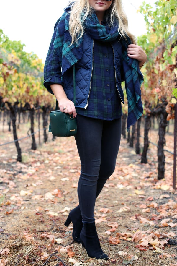 Bows & Sequins wearing a plaid shirt, quilted vest, grey jeans, black booties, and a blanket scarf in Napa, California.