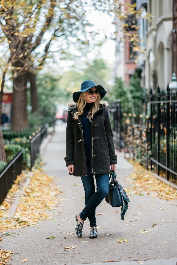 Bows & Sequins styling a fall outfit: floppy hat, dark green toggle coat, Rag & Bone skinny jeans, Gucci loafers, Tom Ford sunglasses, and a Kate Spade bag.