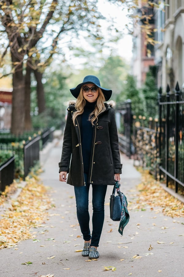 Bows & Sequins styling a fall outfit: floppy hat, dark green toggle coat, Rag & Bone skinny jeans, Gucci loafers, Tom Ford sunglasses, and a Kate Spade bag.
