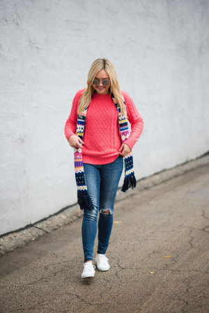 Bows & Sequins wearing a neon pink sweater with a fair isle scarf, blue jeans, and white sneakers