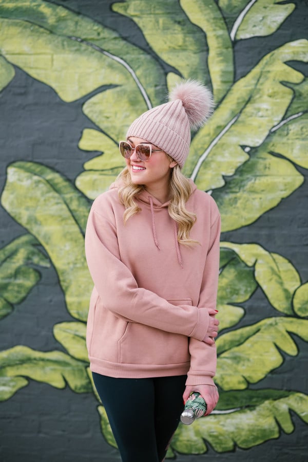 Bows & Sequins wearing a blush pink beanie, sunglasses, and sweatshirt.