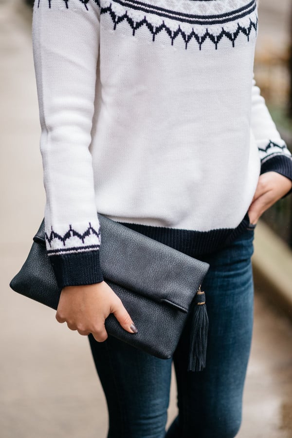 Bows & Sequins wearing a fair isle sweater and navy blue leather tassel clutch.