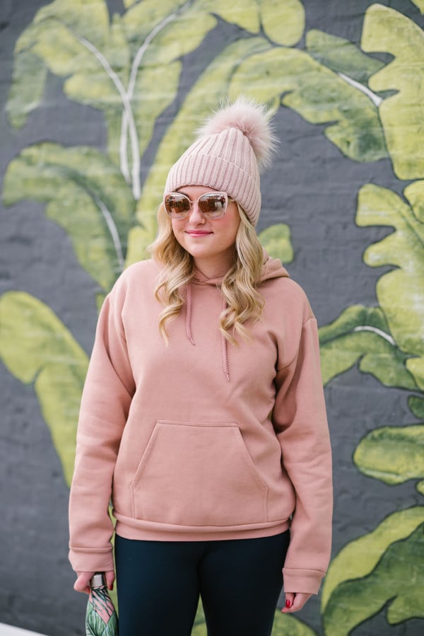 Bows & Sequins wearing a blush pink fur pom pom beanie, rose gold sunglasses, and a pink sweatshirt at Eden Chicago.