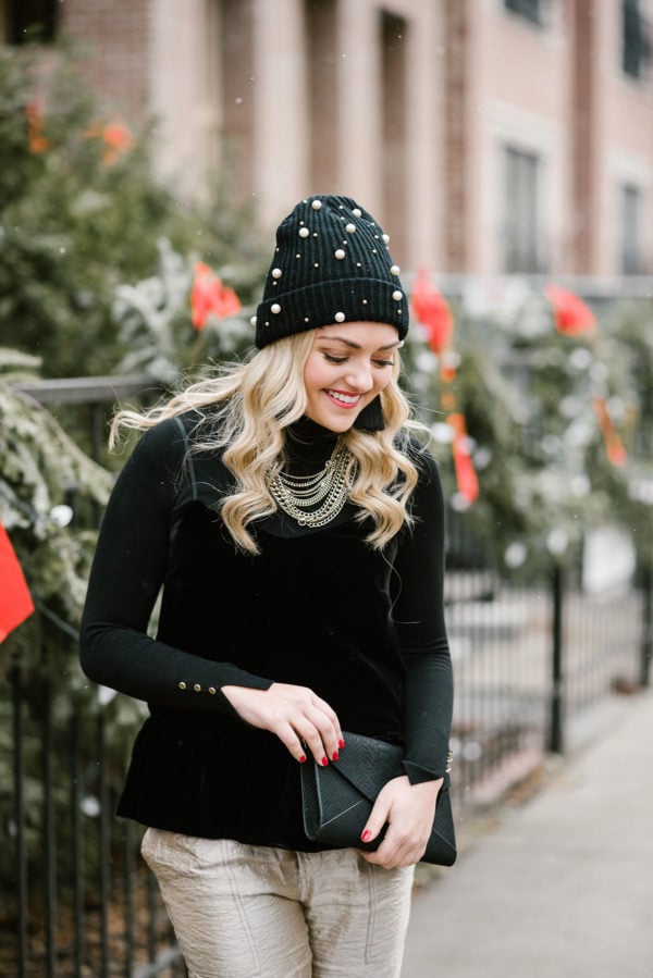 Bows & Sequins wearing a black and gold holiday outfit: black turtleneck, black velvet cami, gold pants, and a pearl embellished beanie.