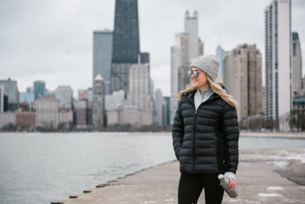 Bows & Sequins wearing a black puffer jacket by Lake Michigan in Chicago. Oak Street Beach has great views of the Chicago skyline!