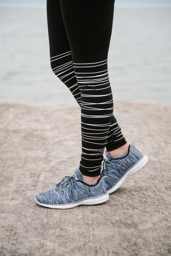 Bows & Sequins wearing black and white striped workout leggings with APL sneakers.