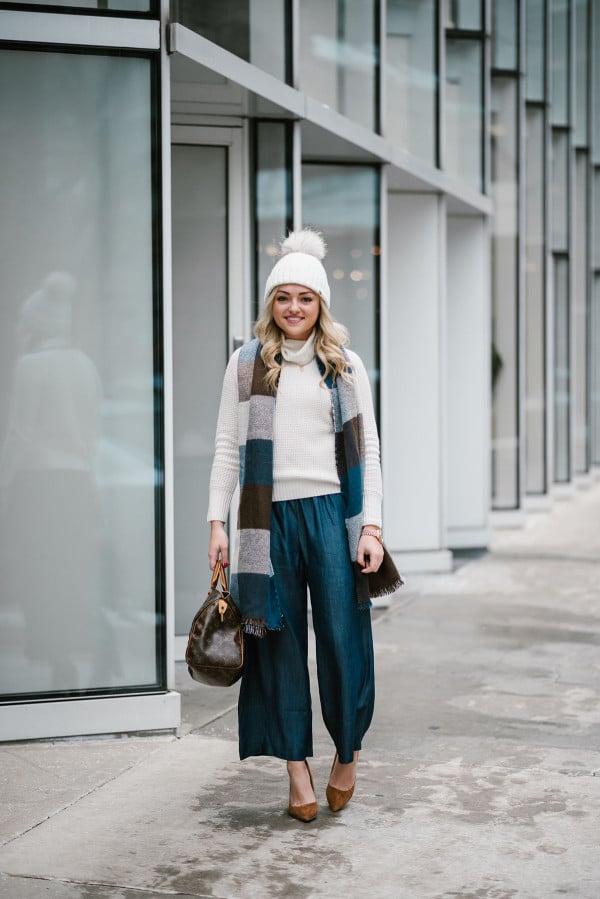Bows & Sequins wearing a fur pom beanie, Uniqlo turtleneck sweater, chambray wide leg pants, pointed toe suede pumps, and a Louis Vuitton Speedy bag.
