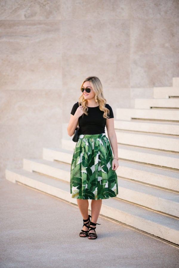 Bows & Sequins in a palm leaf patterned midi skirt with a black crop top and Ray-Ban aviators.
