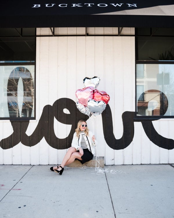 Bows & Sequins styling a black and white outfit for Valentine's Day in front of a LOVE wall.