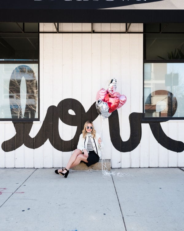 Bows & Sequins styling a black and white outfit for Valentine's Day in front of a LOVE mural l in Chicago.