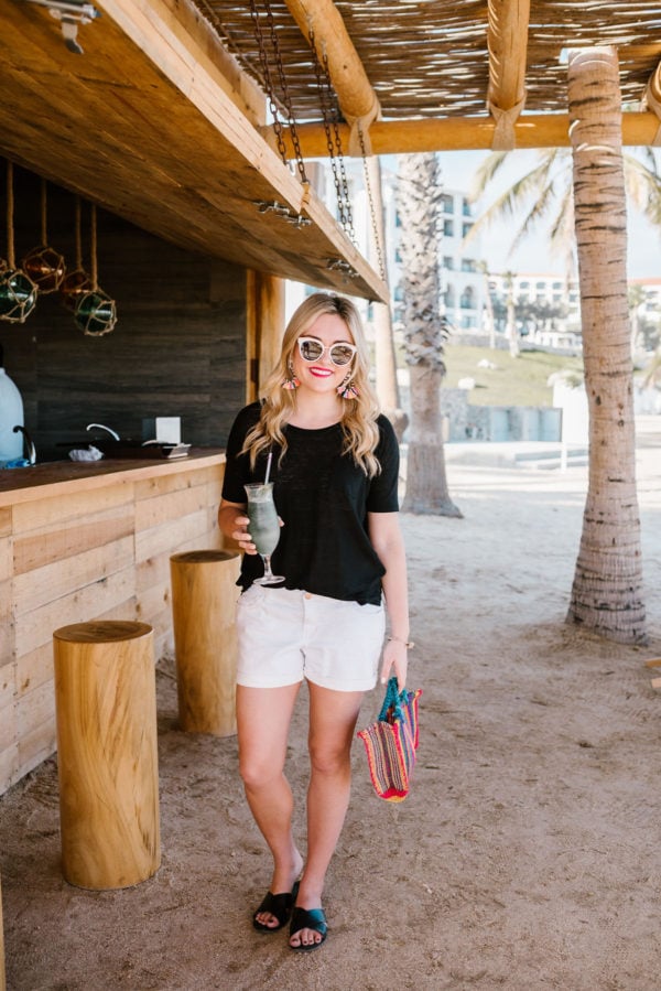 Bows & Sequins wearing a black tee and white boyfriend shorts with a colorful Mexican bag.