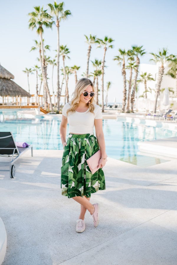 Bows & Sequins wearing a palm leaf patterned skirt with a pink crop top and pink sneakers in Cabo.