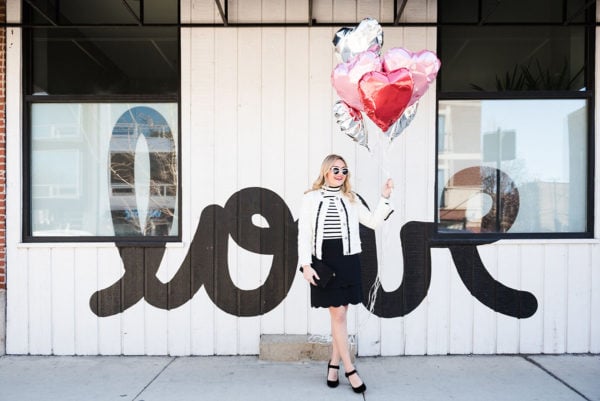 Bows & Sequins wearing a black and white outfit in front of the LOVE wall in Chicago in Bucktown.
