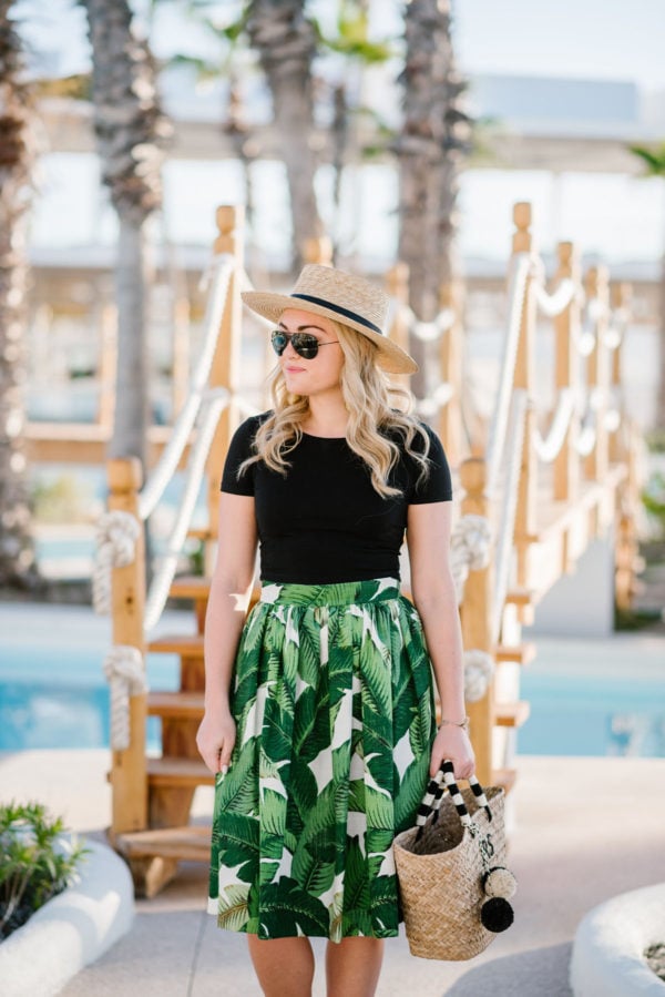 Chicago lifestyle blogger Bows & Sequins styling a Kayu straw tote with a Party Skirts classic palm leaf design with a black crop top.