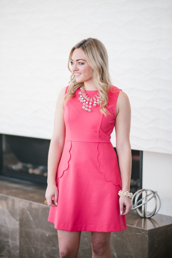 Bows & Sequins waring a pink dress with a statement necklace.