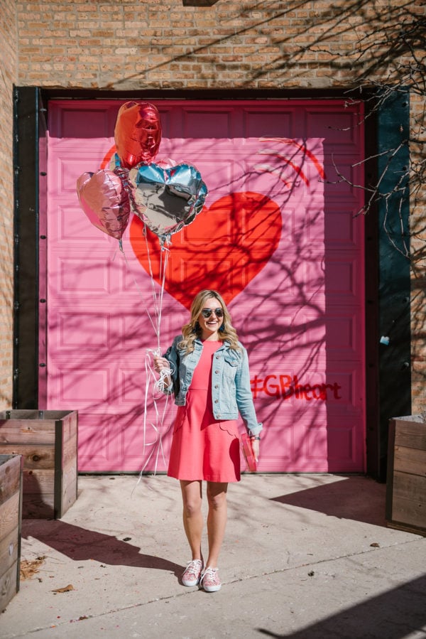 Bows & Sequins styling a pink dress in front of the Pink and Red Heart Garage Door in Chicago.