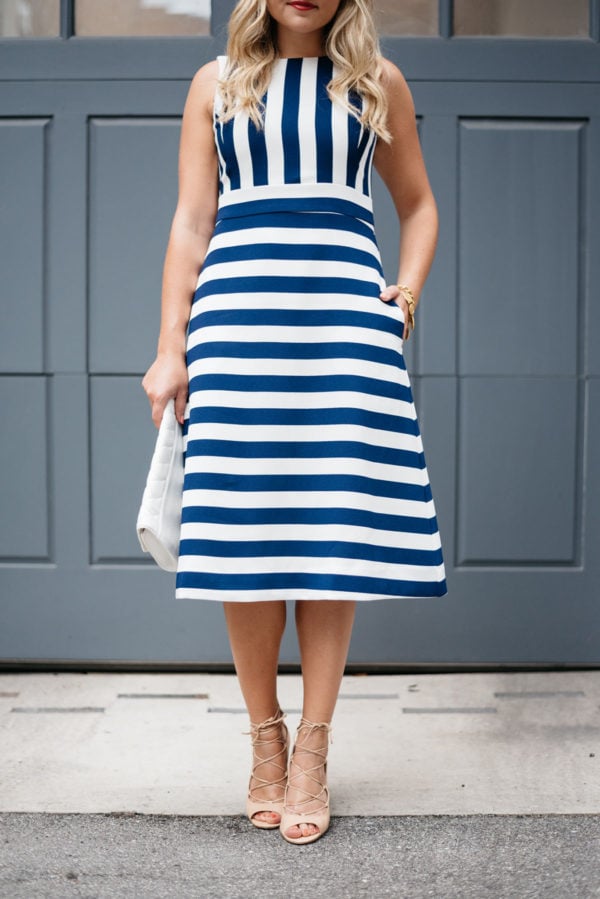 Bows & Sequins wearing a blue and white striped dress with nude heels and a white clutch.