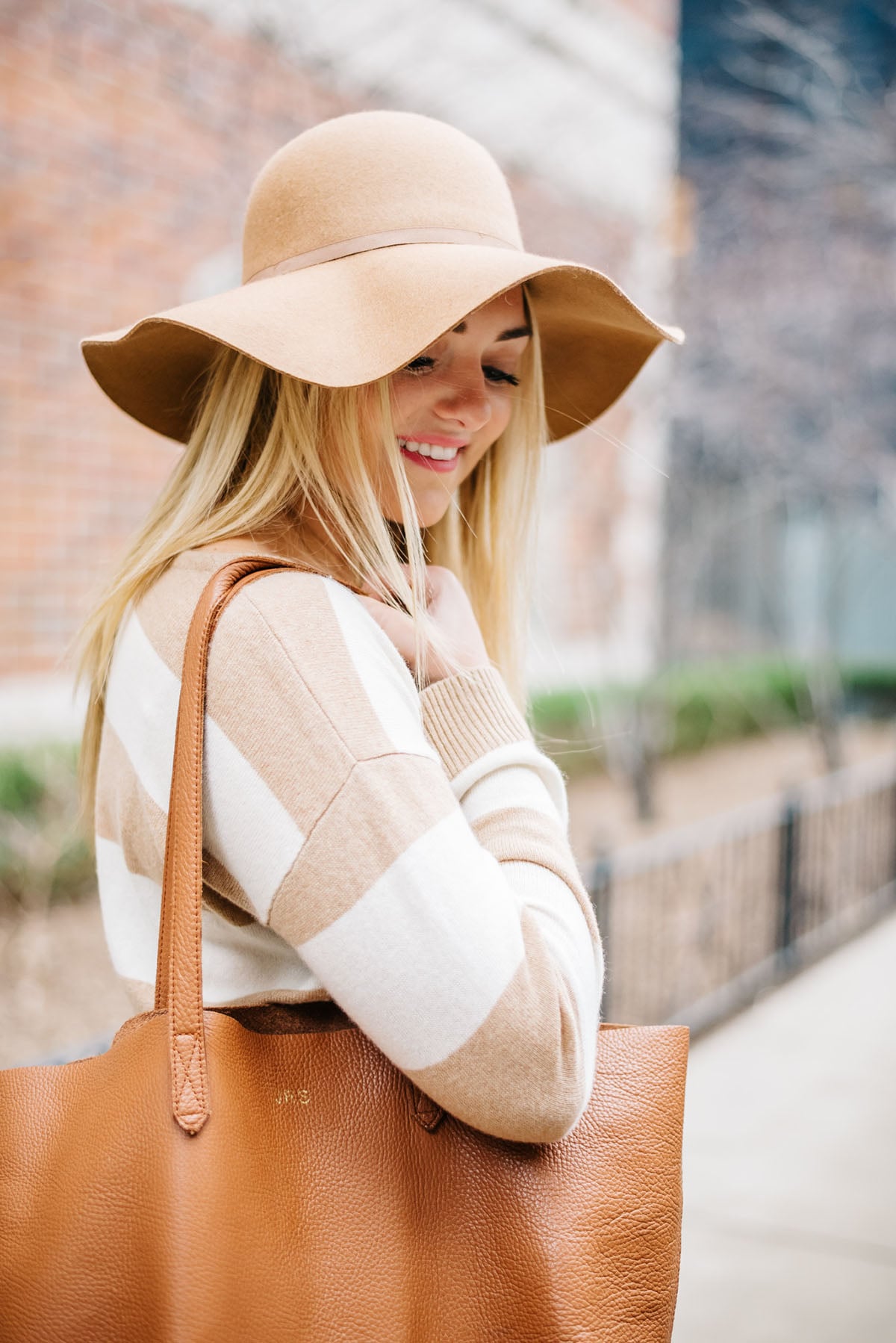 Bows & Sequins wearing a camel hat, striped sweater, and monogrammed leather Cuyana tote.