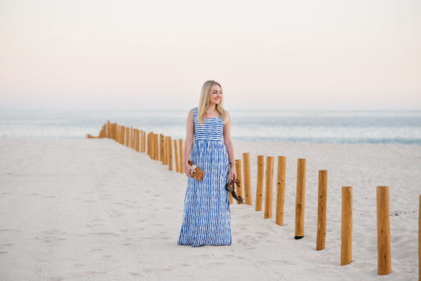 Travel blogger Bows & Sequins wearing a blue striped maxi dress on the beach in Cabo, Mexico.