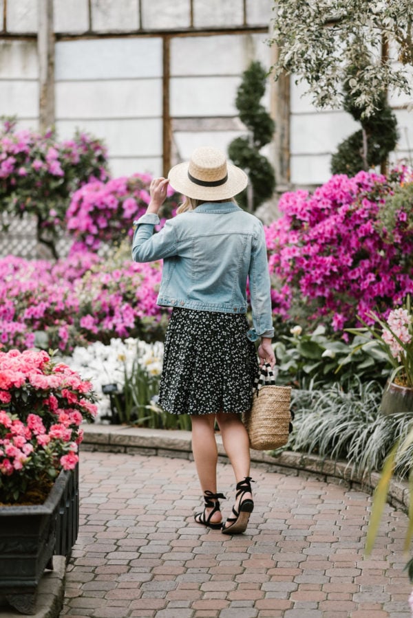 Lifestyle blogger Bows & Sequins accessorizing a floral Old Navy dress with black lace-up sandals and a straw hat.
