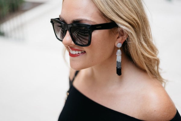 Bows & Sequins accessorizing her outfit with Valentino sunglasses and tassel earrings.