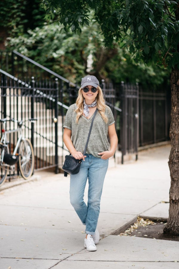 Jessica of Bows & Sequins wearing a Yankees baseball hat, boyfriend jeans, and Stan Smith sneakers.
