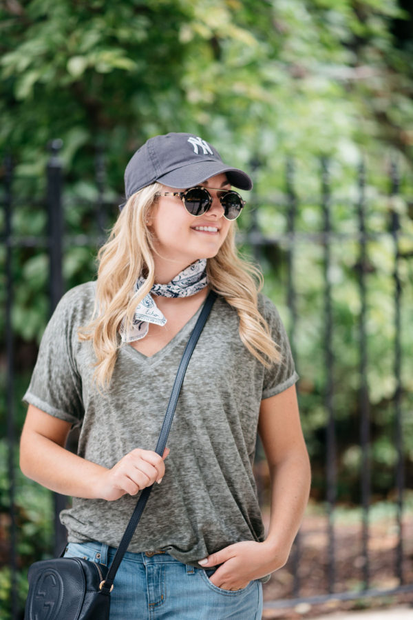 Lifestyle blogger Bows & Sequins wearing a casual outfit for sightseeing in Amsterdam: a baseball hat, bandana, and Illesteva sunglasses.