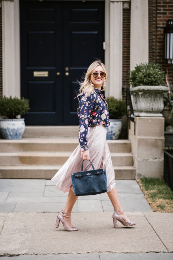 Fashion blogger Bows & Sequins wearing a navy floral blouse and a blush pink midi skirt with glitter pink Kate Spade pumps.