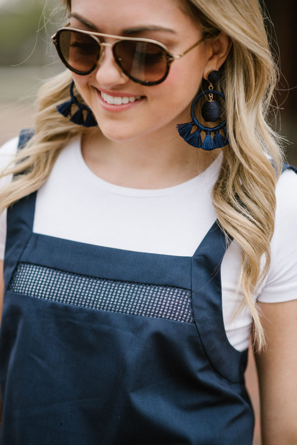 Bows & Sequins wearing Celine sunglasses and navy blue tassel earrings with a white tee shirt and a mesh navy blue jumpsuit.