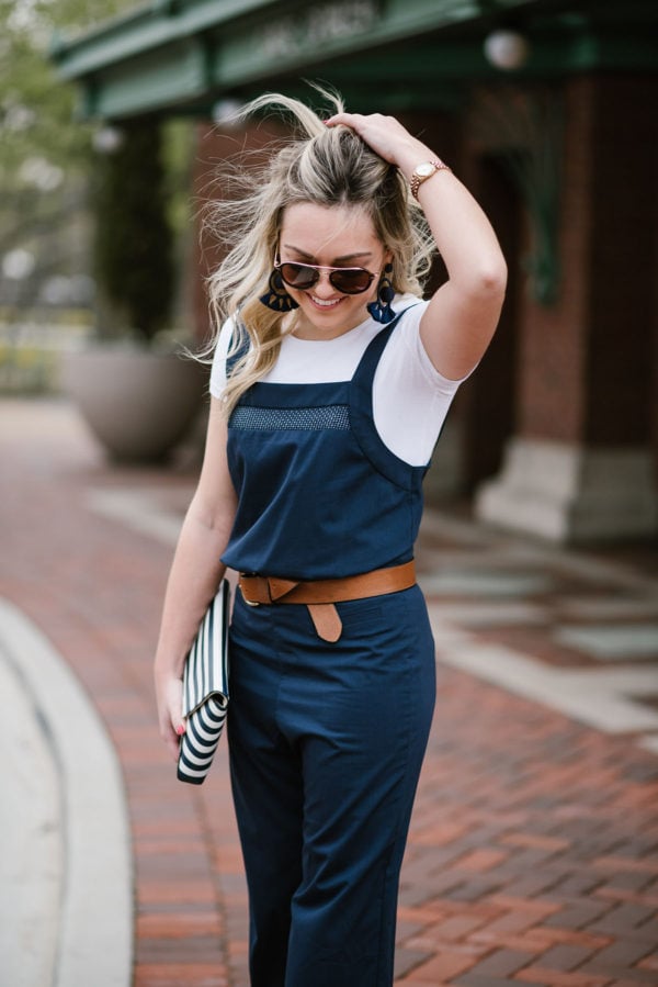 Blogger Bows & Sequins wearing a navy blue jumpsuit with a white tee layered underneath.