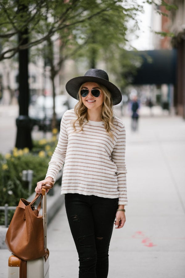 Travel blogger Bows & Sequins wearing a black Janessa Leone hat, striped Kenzie sweater, and black jeans.