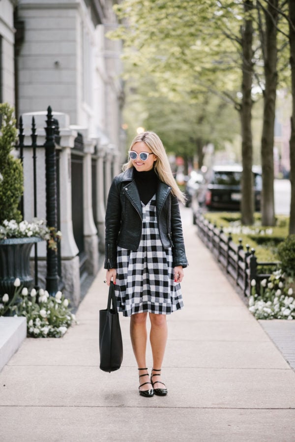 Bows & Sequins wearing a black gingham midi dress with a moto jacket, a leather tote, and strappy Mary Janes.