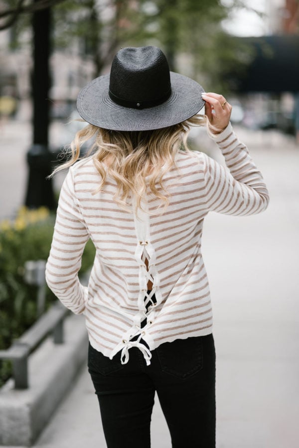 Bows & Sequins wearing a Kenzie tie-back sweater with a black straw hat and Old Navy jeans.