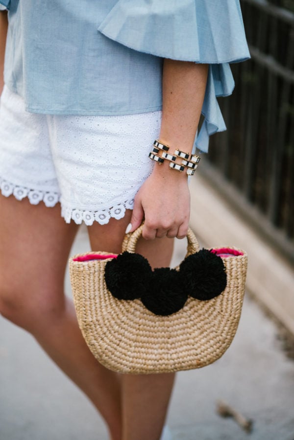 Chicago fashion blogger Bows & Sequins styling a JadeTribe pom pom bag with a Lele Sadoughi bracelet and Kensie eyelet shorts.