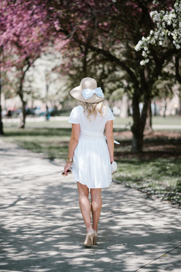 Bows & Sequins wearing a little white dress with a bow hat in Chicago.