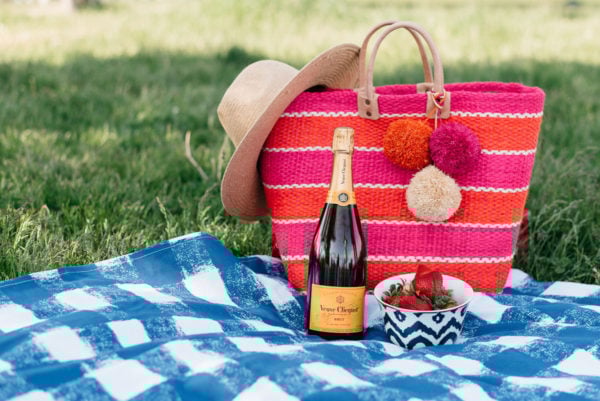 An Old Navy straw hat with a Mar y Sol striped tote on a blue gingham picnic blanket.