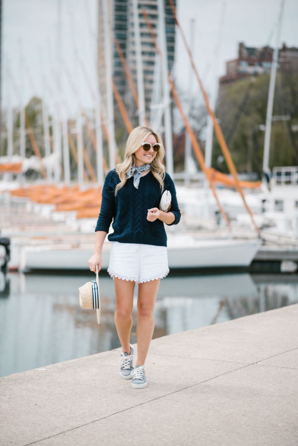 Bows & Sequins wearing a navy summer sweater and white eyelet shorts with gingham shoes, Nordstrom sunglasses, and a straw hat.