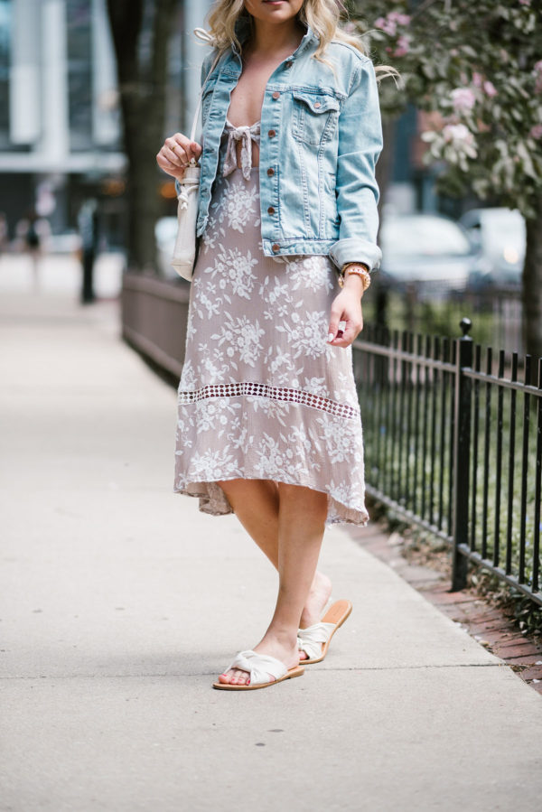Jessica of Bows & Sequins wearing an ASTR tie-front floral midi dress with a Gap jean jacket, Soludos knotted slides, and a Clare V Petit Henri bag.