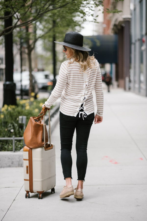 Lifestyle blogger Bows & Sequins sharing her top tips for traveling comfortably. Wearing a Kenzie tie-back sweater and Janessa Leone straw hat.