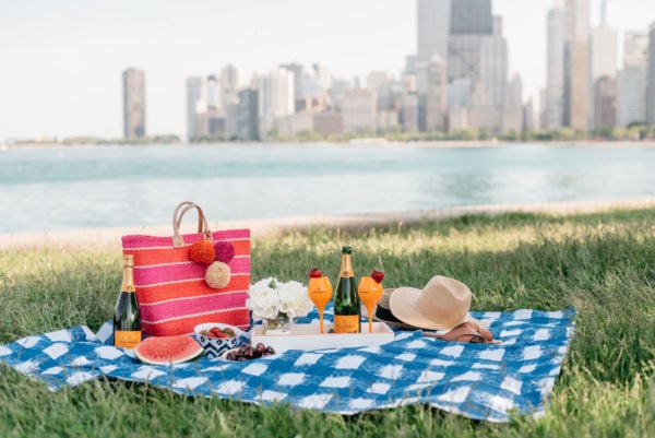 Bows & Sequins hosting a picnic along Lake Michigan with a striped tote and Veuve Clicquot champagne.