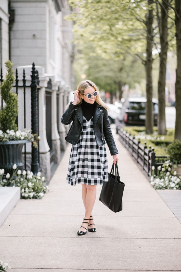 Lifestyle blogger Bows & Sequins wearing a Modcloth gingham midi dress with a moto jacket, leather tote, and Nordstrom black & white sunglasses.