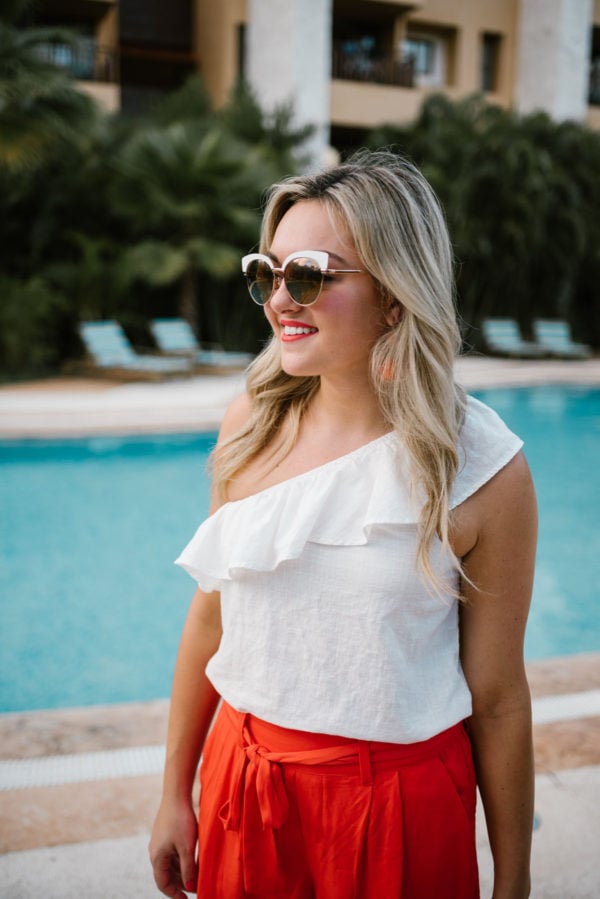 Travel writer Bows & Sequins wearing white rim mirrored sunglasses and an Old Navy one-shoulder ruffle top in Mexico.