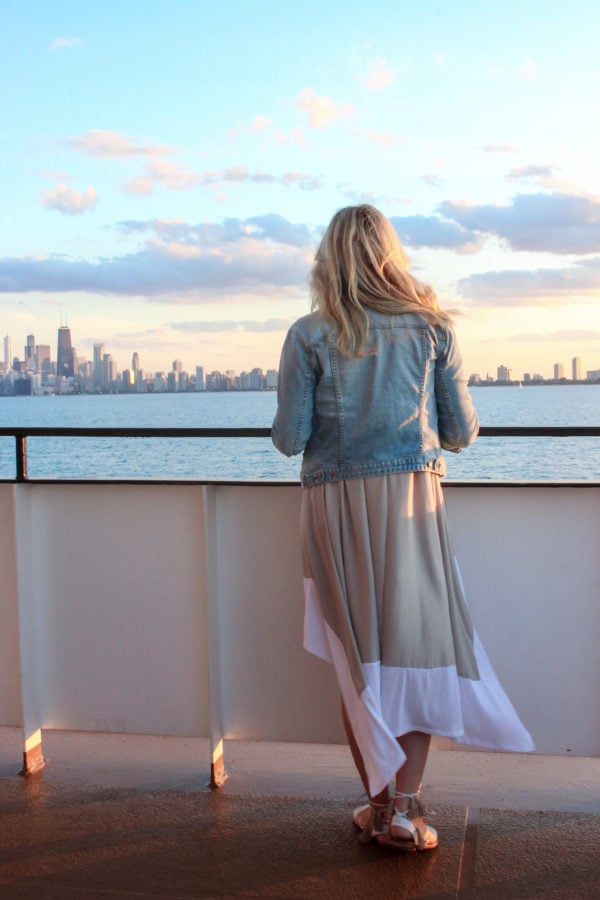 Chicago fashion blogger Bows & Sequins on a boat on Lake Michigan with the Chicago skyline in the background at sunset.