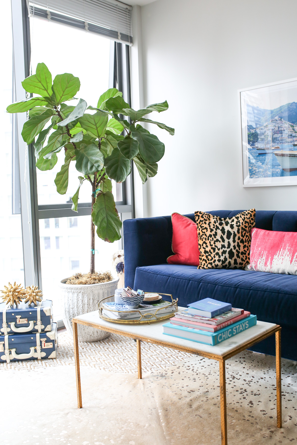 Bows & Sequins living room decor with a gold and white marble coffee table, Society Social navy velvet couch, pink and leopard throw pillows.