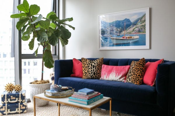 Bows & Sequins living room decor with a fiddle leaf fig, stacked trunks, Gray Malin print, Society Social velvet couch, pink and leopard throw pillows